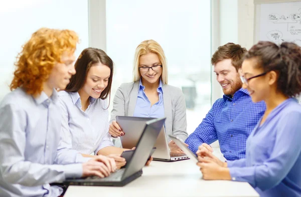 Glimlachend team met laptop en tafel pc-computers — Stockfoto