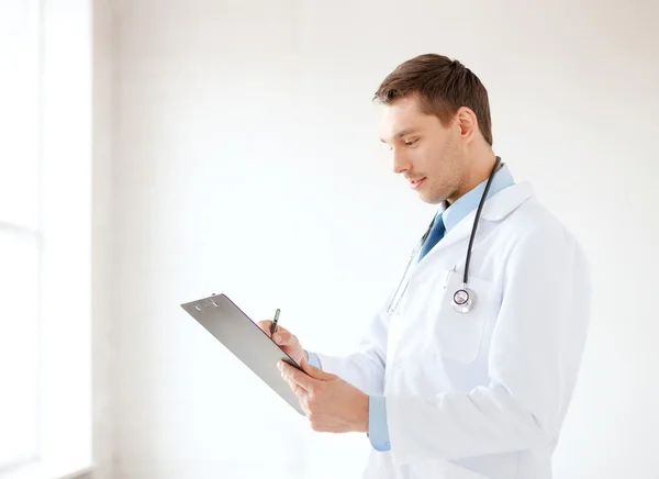 Улыбающийся врач-мужчина со стетоскопом и планшетом — стоковое фото