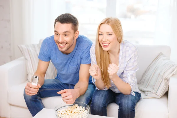 Pareja sonriente con palomitas de maíz animando equipo deportivo —  Fotos de Stock