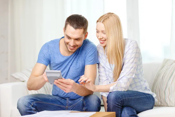 Couple souriant avec papiers et calculatrice à la maison — Photo