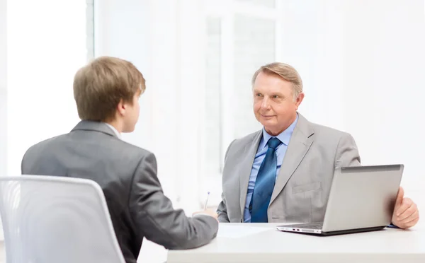 Older man and young man signing papers in office — Stock Photo, Image