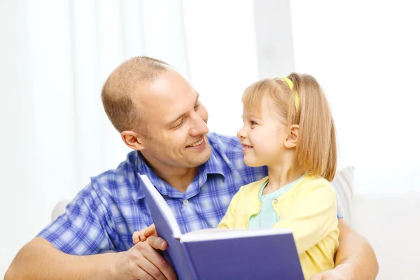 Sonrientes padre e hija con libro en casa Imágenes de stock libres de derechos