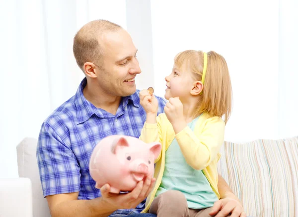Gelukkig vader en dochter met grote piggy bank Stockafbeelding