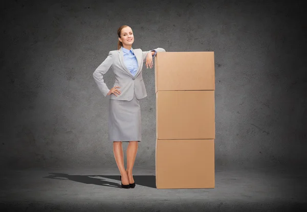 Smiling businesswoman with cardboard boxes — Stock Photo, Image