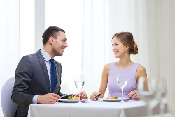 Sonriente pareja comiendo plato principal en restaurante — Foto de Stock