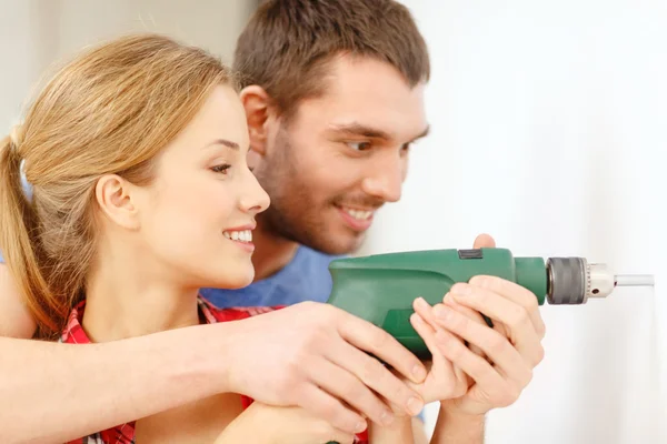 Casal sorridente furo de perfuração na parede em casa — Fotografia de Stock