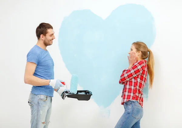 Улыбающаяся пара рисует большое сердце на стене — стоковое фото