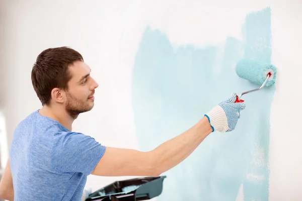 Uomo sorridente pittura muro a casa — Foto Stock