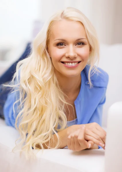 Sorridente giovane donna sdraiata sul divano a casa — Foto Stock