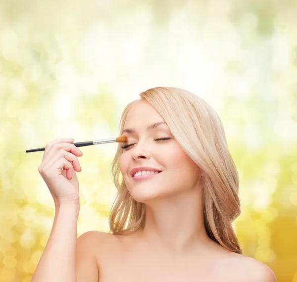 Vacker kvinna med slutna ögon och makeup borste — Stockfoto