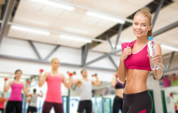 Sporty woman with bottle of water and towel — Stock Photo, Image