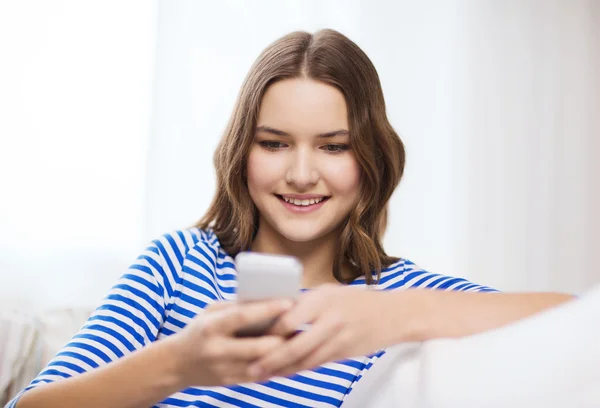 Sonriente adolescente con teléfono inteligente en casa — Foto de Stock