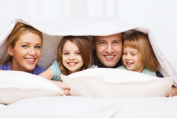 Famille heureuse avec deux enfants sous couverture à la maison — Photo