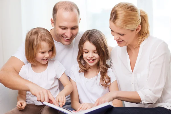 Familia sonriente y dos niñas con libro —  Fotos de Stock