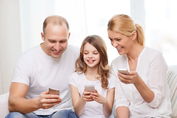 Vanhemmat ja pieni tyttö älypuhelimet kotona — kuvapankkivalokuva