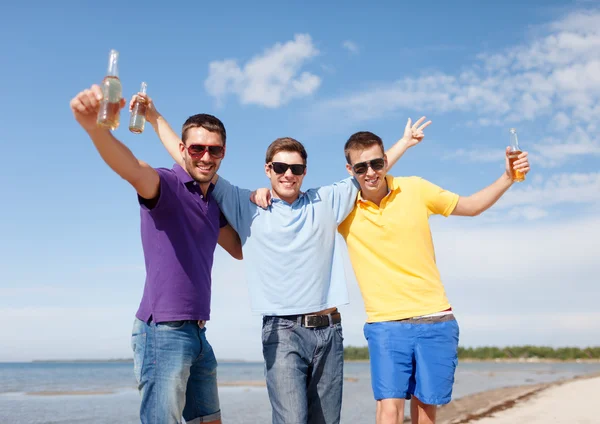 Друзья веселятся на пляже с бутылками пива — стоковое фото