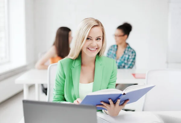 Lächelndes junges Mädchen liest Buch in der Schule — Stockfoto