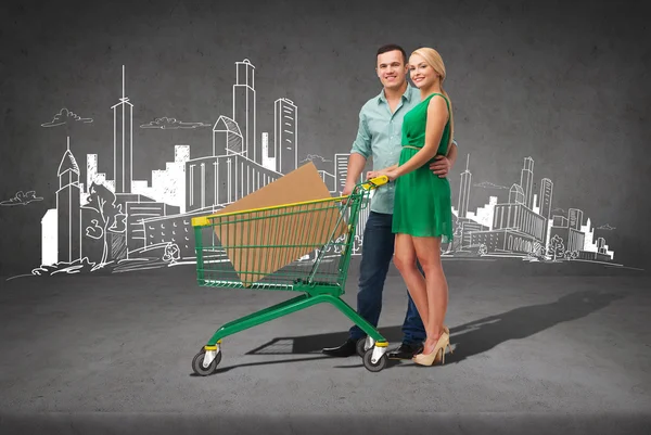 Usmívající se pár s nákupním košíkem a velkou krabici — Stock fotografie