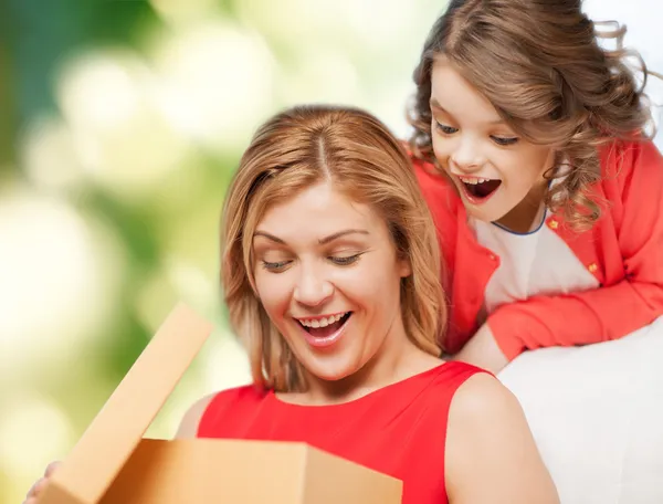 Улыбающиеся мать и дочь открывают подарочную коробку — стоковое фото