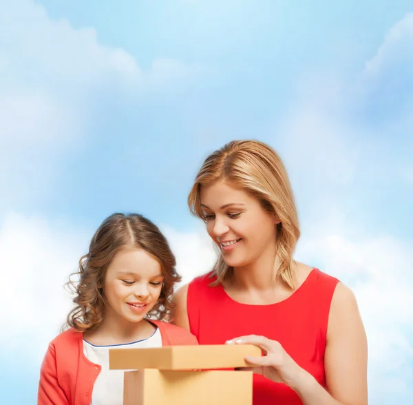 Улыбающиеся мать и дочь с подарочной коробкой — стоковое фото