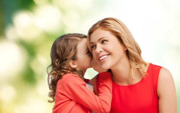 Sonrientes madre e hija susurrando chismes —  Fotos de Stock