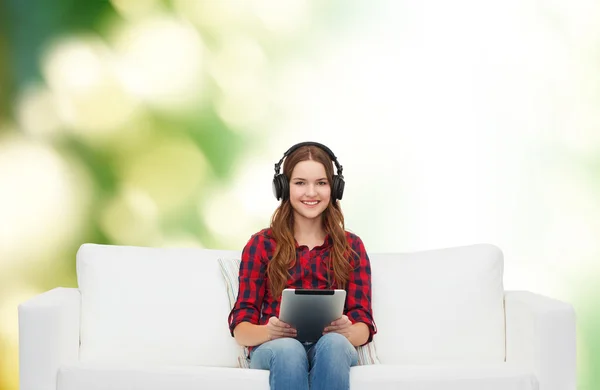 Fille assise sur le canapé avec écouteurs et tablette PC — Photo