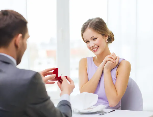 Excited young woman looking at boyfriend with ring — Stock Photo, Image