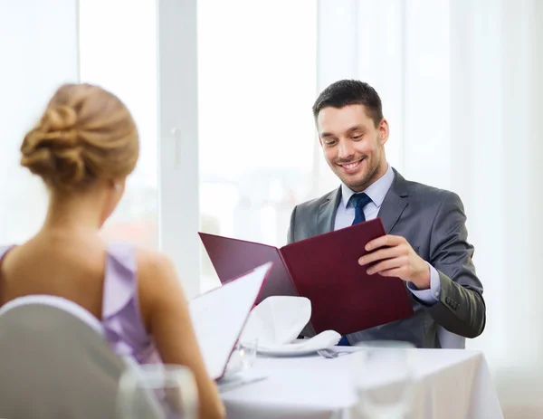 Joven sonriente mirando el menú en el restaurante — Foto de Stock