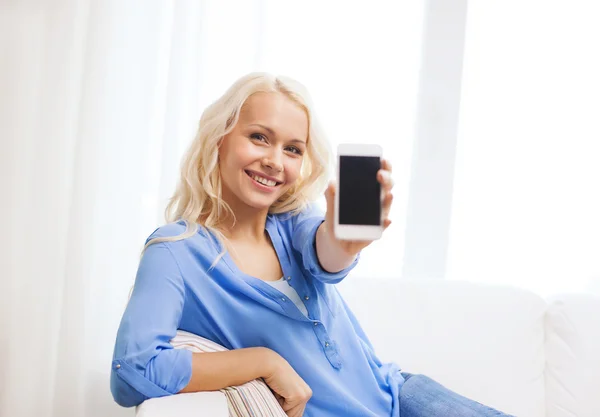 Lachende vrouw met lege smartphone scherm thuis — Stockfoto