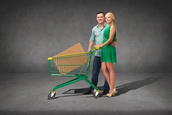 Pareja sonriente con carrito de compras y caja grande —  Fotos de Stock