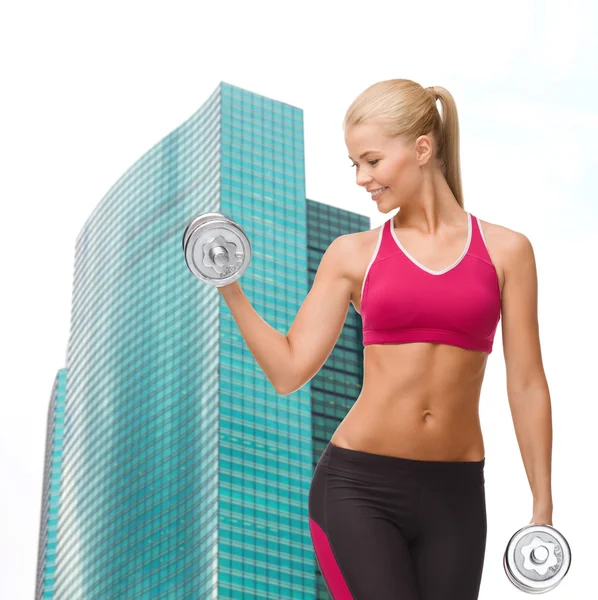 Smiling woman lifting steel dumbbell — Stock Photo, Image