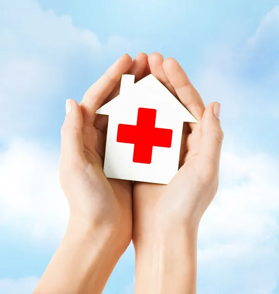 Händer som håller papper hus med röda korset — Stockfoto