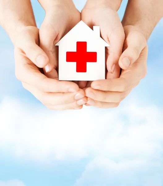 Hands holding paper house with red cross — Stock Photo, Image