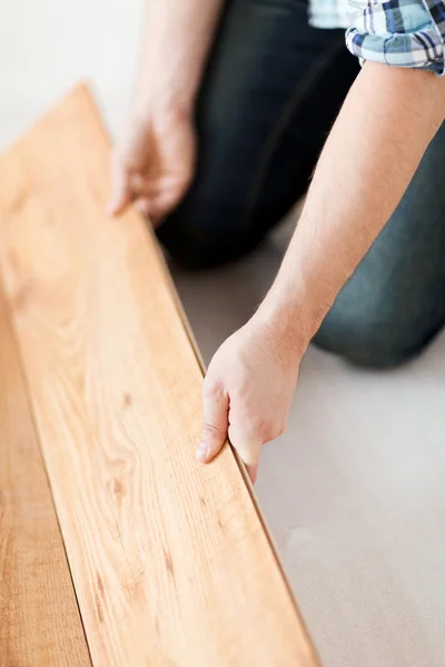 Primo piano di mani maschili intalling pavimento in legno — Foto Stock