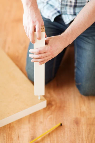 Primo piano di mani maschili assemblaggio gambe a tavola — Foto Stock