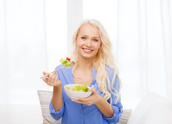 Leende ung kvinna med grön sallad hemma — Stockfoto