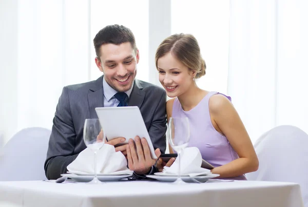 Pareja con menús en la tableta PC en el restaurante — Foto de Stock