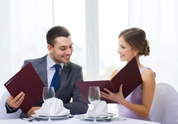 Smiling couple with menus at restaurant — Stock Photo, Image