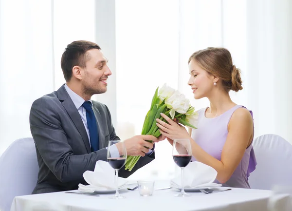 Hombre sonriente dando ramo de flores en el restaurante — Foto de Stock