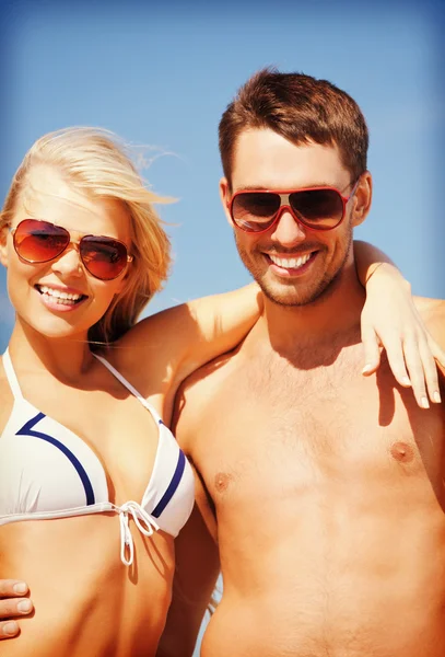 Pareja feliz en gafas de sol en la playa — Foto de Stock