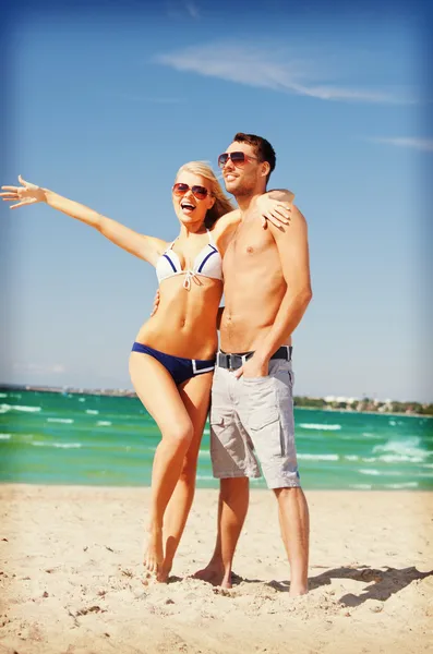 Casal feliz em óculos de sol na praia — Fotografia de Stock