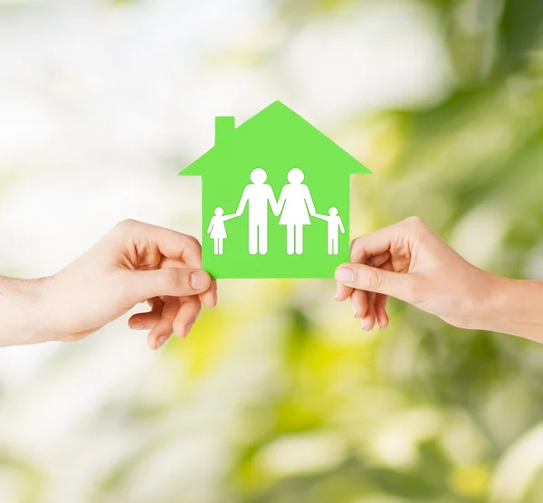 Mãos segurando casa verde com a família — Fotografia de Stock