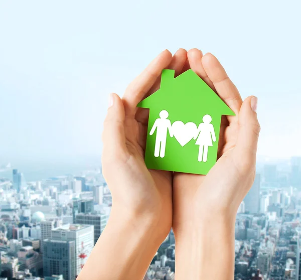 Manos sosteniendo casa verde con la familia —  Fotos de Stock