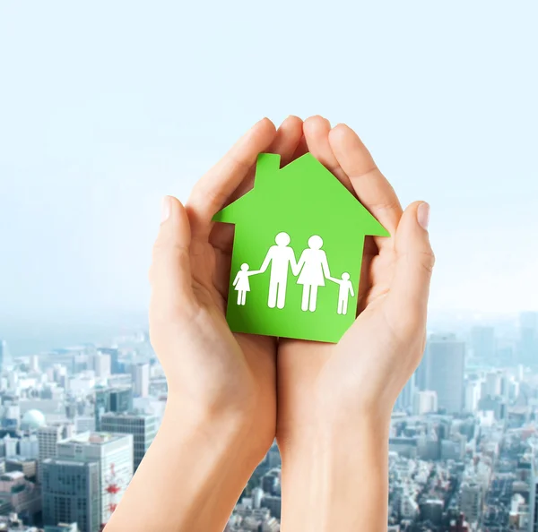 Hands holding green house with family — Stock Photo, Image