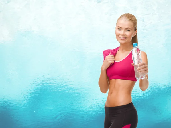Sporty woman with bottle of water and towel — Stock Photo, Image