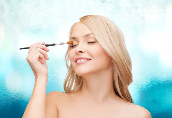 Mooie vrouw met gesloten ogen en make-up borstel — Stockfoto