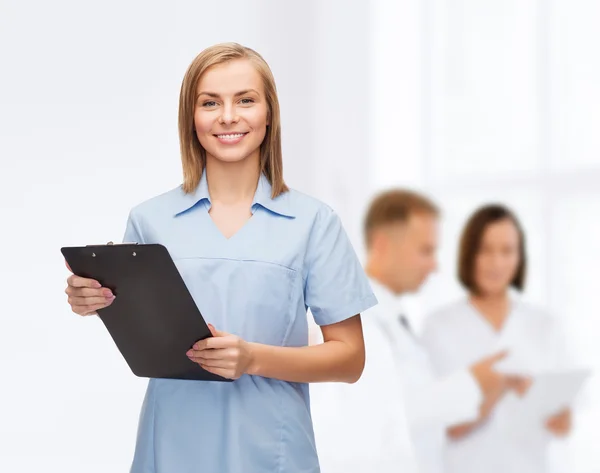 Médico o enfermera sonriente con portapapeles — Foto de Stock