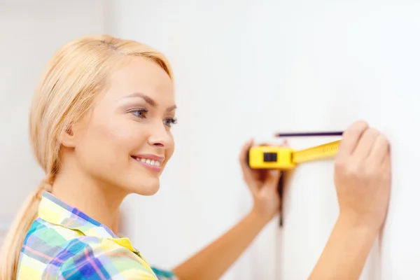 Mujer sonriente que mide la pared —  Fotos de Stock