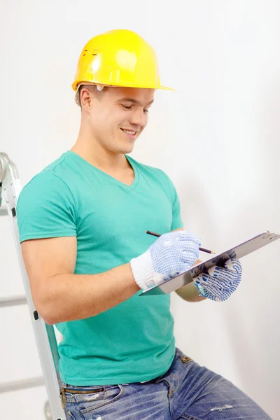 Hombre sonriente en casco protector con portapapeles — Foto de Stock