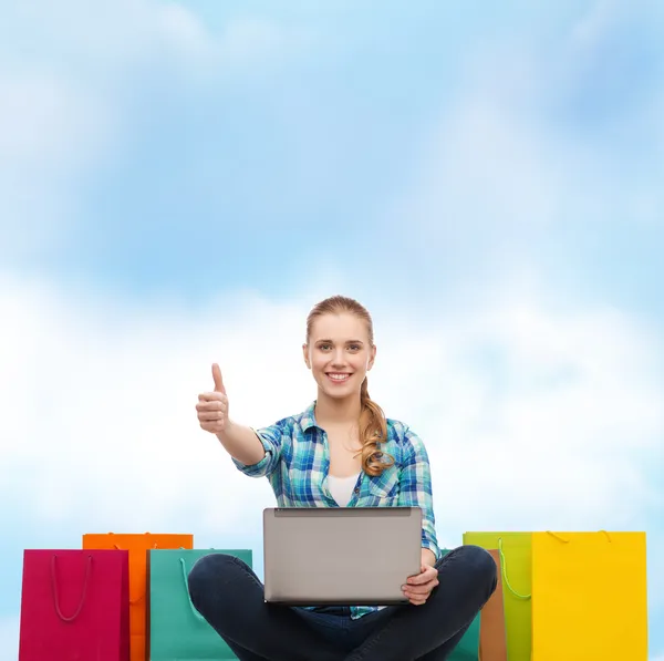 Chica sonriente con ordenador portátil comuter y bolsas de compras —  Fotos de Stock